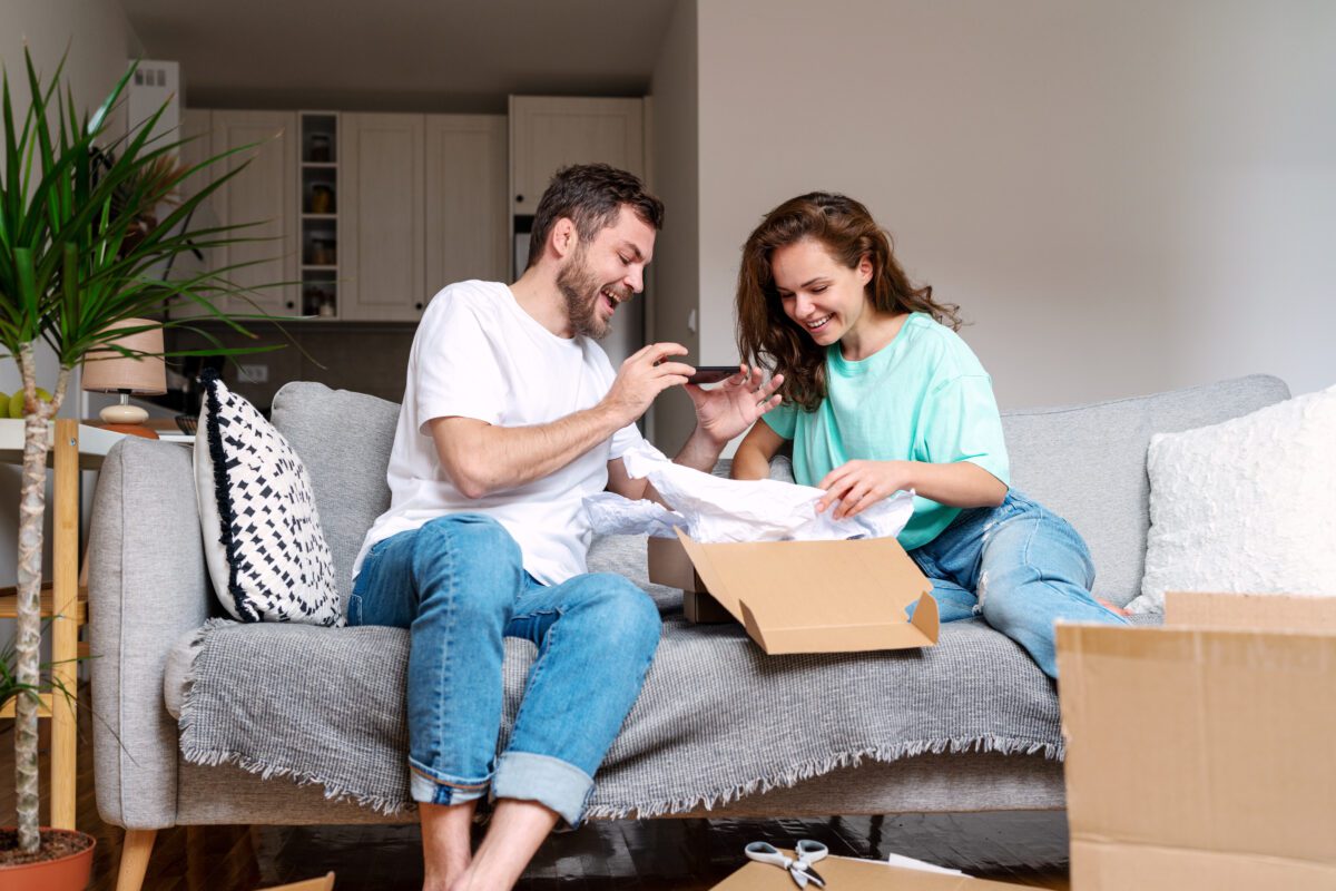 Young couple unboxing their internet order from online sore and photographing purchase for their social media.