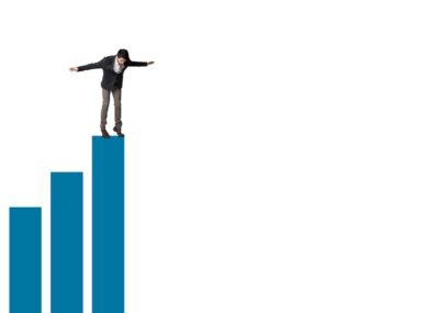 Business Person standing precariously atop a Bar Graph