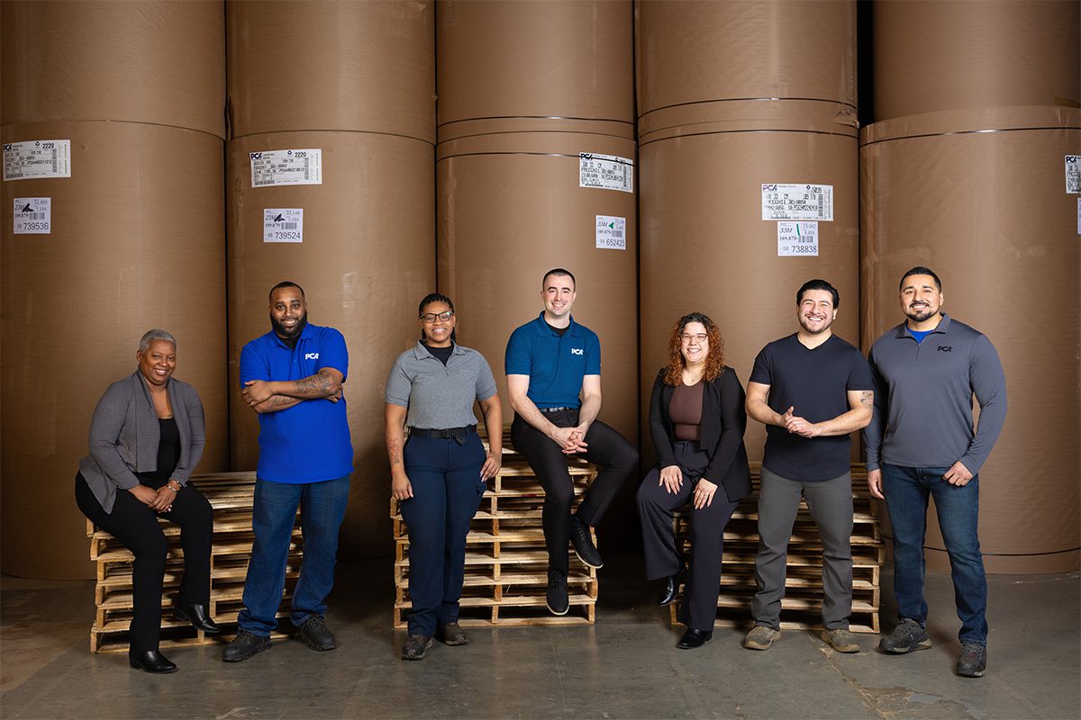 A group of PCA employees in front of roll stock in a box plant
