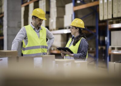 Two Workers in a Warehouse Filled with Boxes