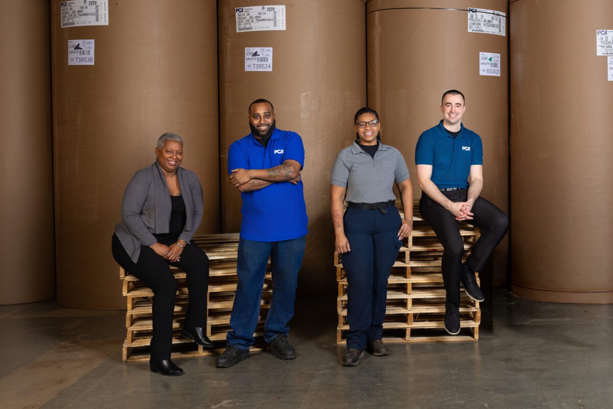 A group of PCA employees in front of roll stock in a box plant